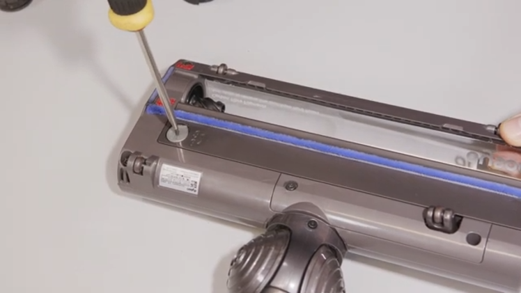 Use a flathead screwdriver in the cap at the side and turn in the direction of the arrow to unlock the motorhead guard