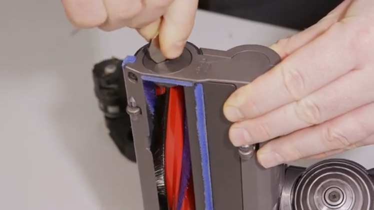 Remove the brushbar from the motorhead by placing a coin into the slot in the cap and turning in the direction of the arrow above the cap
