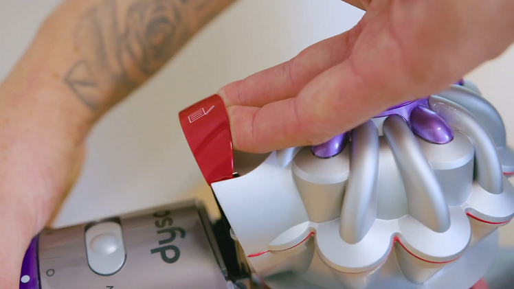 Hold the vacuum/bin firmly and pull the red lever up at the top of the vacuum.